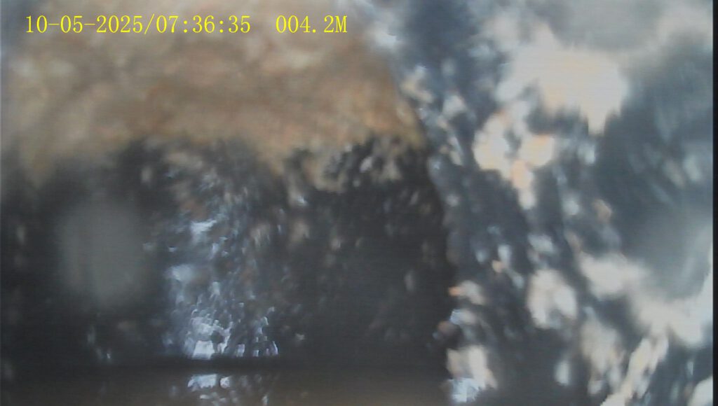 Abwasserrohr mit sichtbaren Wandablagerungen und Sediment.