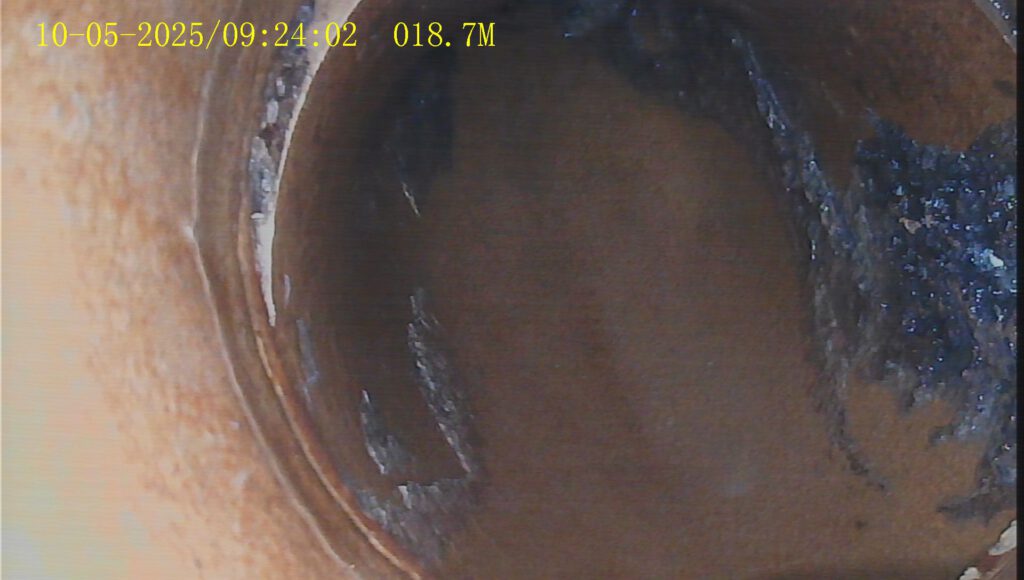 Kamerabild eines runden Schachtes oder Rohrübergangs mit Ablagerungen.