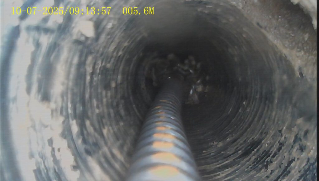 Rohrkamera zeigt stark verschmutztes Abwasserrohr mit Ablagerungsringen.