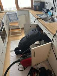 Rohrreiniger arbeitet am Küchenabfluss unter der Spüle